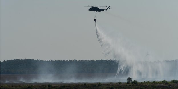 Ein Hubschrauber verteilt Wasser über dem Moor bei Meppen. Ein Hubschrauber verteilt Wasser über dem Moor bei Meppen.