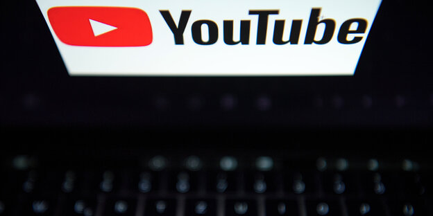 Ein Laptop von oben, auf dessen Bildschirm das Youtube-Loge: ein weißes nach rechts zeigendes Dreieck auf einem roten rechteckigen Hintergrund Ein Laptop von oben, auf dessen Bildschirm das Youtube-Loge: ein weißes nach rechts zeigendes Dreieck auf einem roten rechteckigen Hintergrund