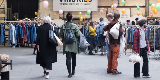 Kleiderständer stehen in einer Halle, Menschen stehen dazwischen. Kleiderständer stehen in einer Halle, Menschen stehen dazwischen.
