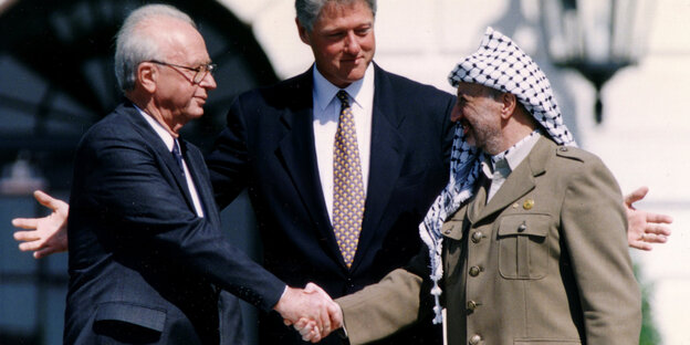 Arafat und Rabin schütteln sich die Hände, Bill Clinton breitet hinter ihnen die Arme aus. Arafat und Rabin schütteln sich die Hände, Bill Clinton breitet hinter ihnen die Arme aus.