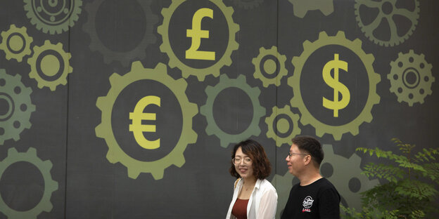 Menschen gehen an einer Wand vorbei, welche die Symbole für den Yen, Euro, Dollar und britischen Pound zeigt Menschen gehen an einer Wand vorbei, welche die Symbole für den Yen, Euro, Dollar und britischen Pound zeigt