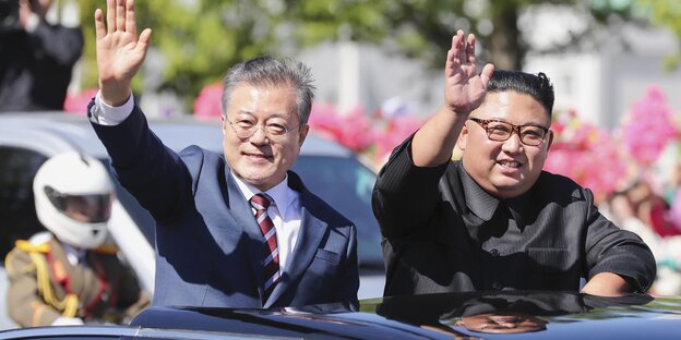 Moon Jae In und Kim Jong Un winken aus einem Auto Moon Jae In und Kim Jong Un winken aus einem Auto