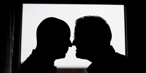 Die Silhouetten von zwei männlichen Profilen vor einem Fenster Die Silhouetten von zwei männlichen Profilen vor einem Fenster