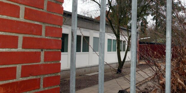 Ein Flachbau hinter Gitterstäben. Ein Flachbau hinter Gitterstäben.