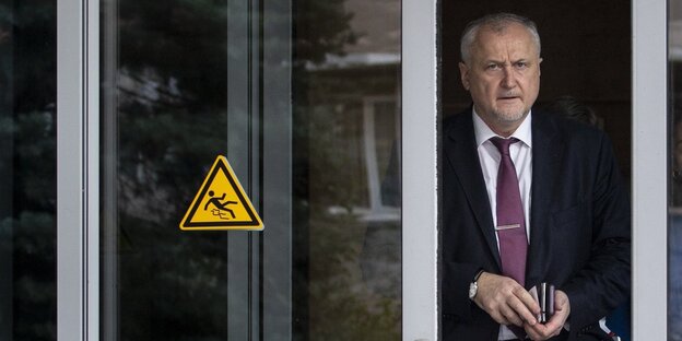 Yuri Ganus verlässt eine Tür mit dem Warnzeichen “Vorsicht, rutschig“ Yuri Ganus verlässt eine Tür mit dem Warnzeichen “Vorsicht, rutschig“