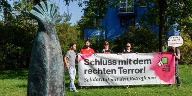 Ein Gedenkstein, daneben Menschen mit einem antifaschistischen Transparent Ein Gedenkstein, daneben Menschen mit einem antifaschistischen Transparent