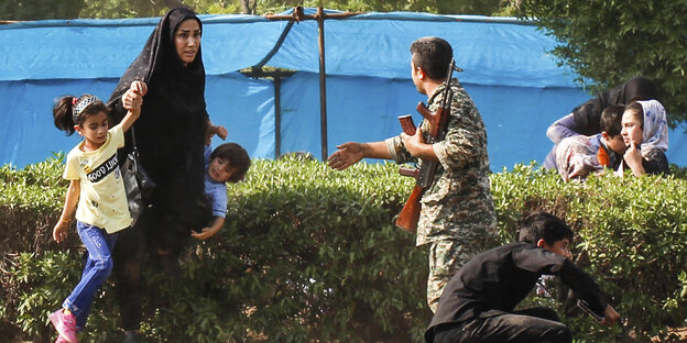 Iranischer Soldat hilft einer Schutz suchenden Frau Iranischer Soldat hilft einer Schutz suchenden Frau