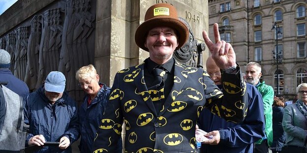 ein Mann in Batman-Sakko macht ein Victory-Zeichen ein Mann in Batman-Sakko macht ein Victory-Zeichen