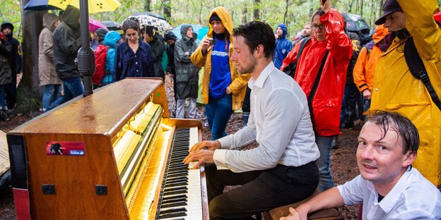 Ein Teilnehmer der Demonstration gegen die Rodung des Hambacher Forsts sitzt im Wald und spielt im Regen Klavier Ein Teilnehmer der Demonstration gegen die Rodung des Hambacher Forsts sitzt im Wald und spielt im Regen Klavier