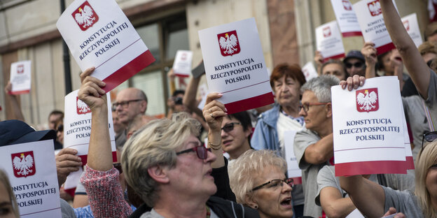 Demonstranten halten Deckblätter der polnischen Verfassung in die Luft Demonstranten halten Deckblätter der polnischen Verfassung in die Luft