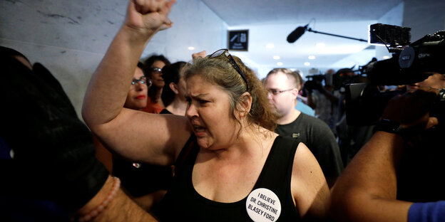 Eine Frau demonstriert gegen Kavanaugh, sie trägt einen Button auf dem steht "I Believe Dr. Christine Blaisey Ford" Eine Frau demonstriert gegen Kavanaugh, sie trägt einen Button auf dem steht "I Believe Dr. Christine Blaisey Ford"
