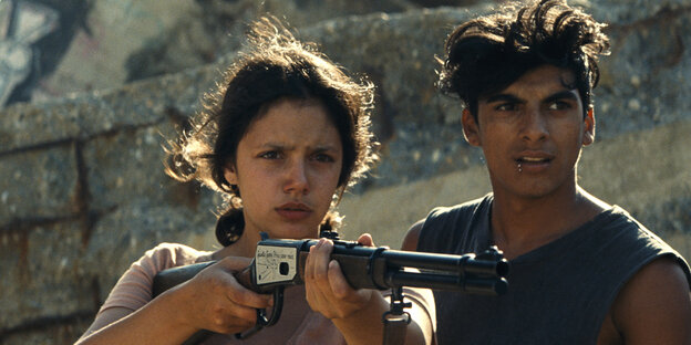 Ava und Juan stehen nebeneinander und sie hält ein Gewehr in der Hand. Ava und Juan stehen nebeneinander und sie hält ein Gewehr in der Hand.