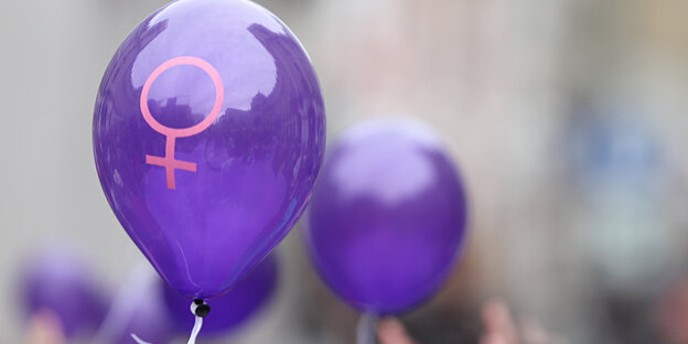 Zwei lila Luftballons mit dem Frauensymbol drauf. Zwei lila Luftballons mit dem Frauensymbol drauf.