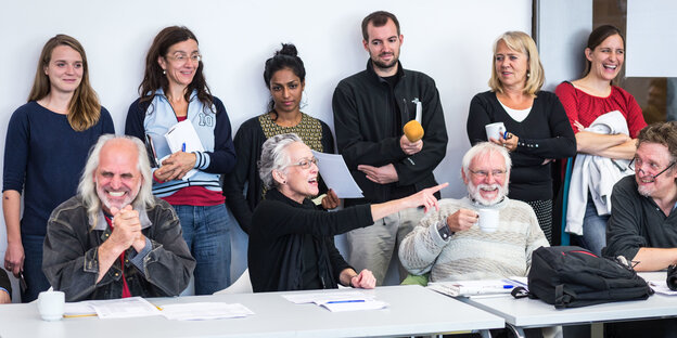 Ältere Herrschaften sitzen, jüngere stehen dahinter Ältere Herrschaften sitzen, jüngere stehen dahinter