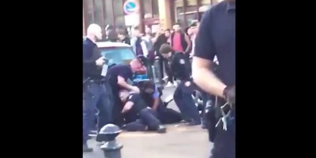 Ein Mann liegt auf dem Boden von Polizisten umringt Ein Mann liegt auf dem Boden von Polizisten umringt