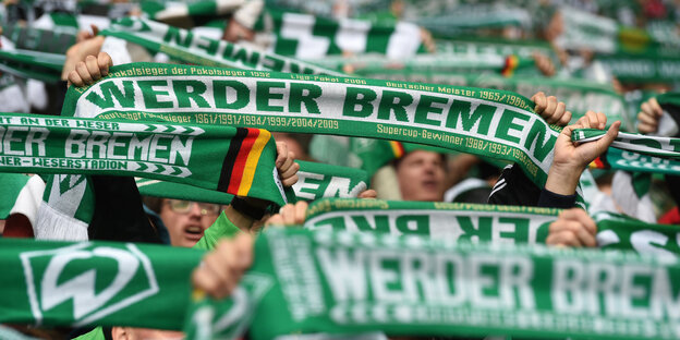 Fans von Werder Bremen halten ihren Schal hoch Fans von Werder Bremen halten ihren Schal hoch