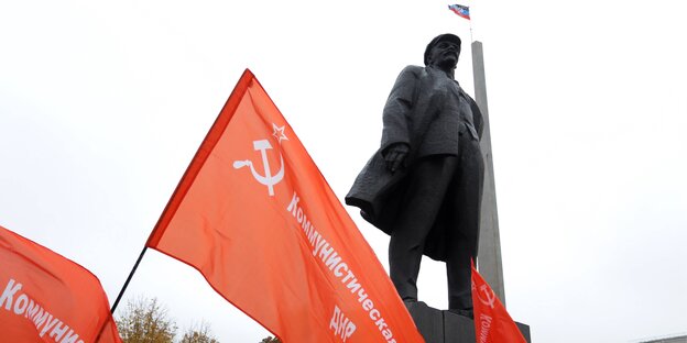 KP-Fahnen unter einem Lenin-Denkmal KP-Fahnen unter einem Lenin-Denkmal