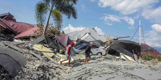 Zwei Menschen laufen über Trümmer in Indonesien Zwei Menschen laufen über Trümmer in Indonesien