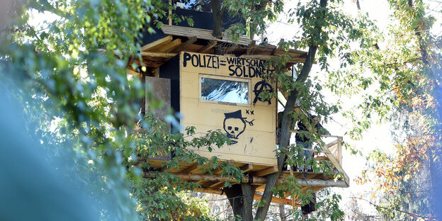 Ein Baumhaus, auf dem steht: Polizei gleich Wirtschaftssolidarität Ein Baumhaus, auf dem steht: Polizei gleich Wirtschaftssolidarität