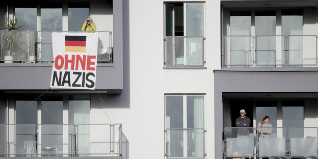 An einer grauen Hausfassade hängt ein Schild auf dem Ohne Nazis steht An einer grauen Hausfassade hängt ein Schild auf dem Ohne Nazis steht