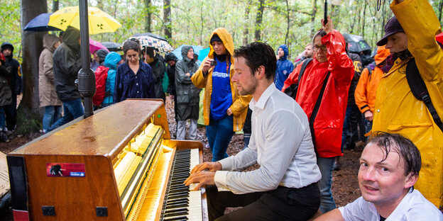 Im Hambacher Forst demonstrieren Menschen gegen die Rodung des Waldes. Ein Mann spielt Klavier Im Hambacher Forst demonstrieren Menschen gegen die Rodung des Waldes. Ein Mann spielt Klavier