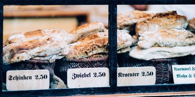 Verschiedene Brotsorten liegen in einer Auslage. Davor stehen Schilder, die die Sorten benennen