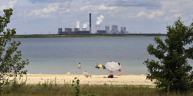 Ein Strand an einem See, der früher ein Tagebau war, dahinter ein großes Kraftwerk Ein Strand an einem See, der früher ein Tagebau war, dahinter ein großes Kraftwerk
