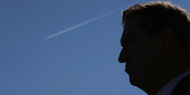 Das Profil eines Mannes, von Markus Söder, vor dem blauen Himmel, an dem ein Kondensstreifen zu sehen ist Das Profil eines Mannes, von Markus Söder, vor dem blauen Himmel, an dem ein Kondensstreifen zu sehen ist