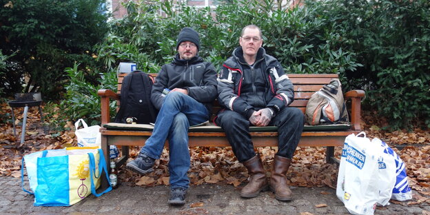 Zwei Obdachlose sitzen auf einer Parkbank. Zwei Obdachlose sitzen auf einer Parkbank.
