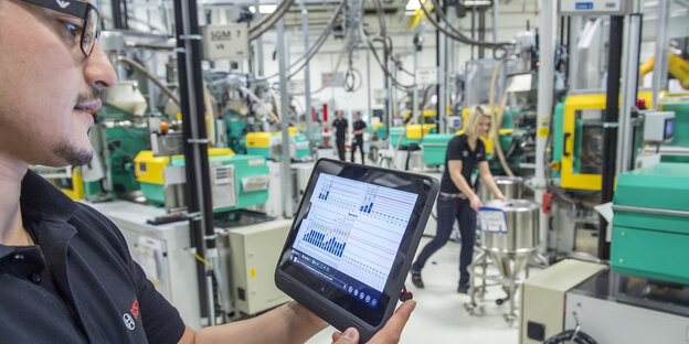 Ein Arbeiter mit einem Tablet in einer Fabrikhalle Ein Arbeiter mit einem Tablet in einer Fabrikhalle