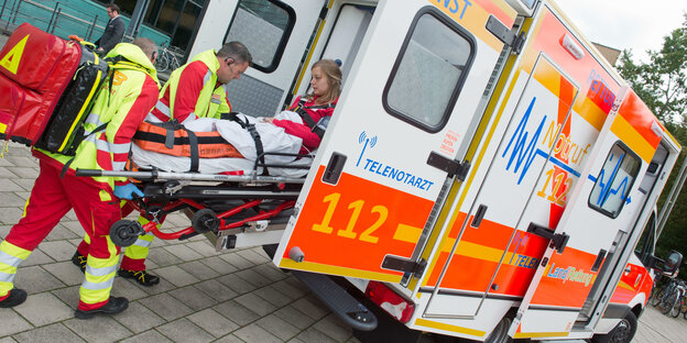 Rettungssanitäter schieben Bahre mit Patientin in Rettungswagen mit der Aufschrift "Telenotarzt" Rettungssanitäter schieben Bahre mit Patientin in Rettungswagen mit der Aufschrift "Telenotarzt"