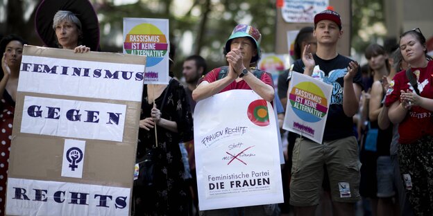 Demonstrantinnen klatschen in die Hände, tragen u.a. ein Plakat mit der Aufschrift "Feminimus gegen rechts"