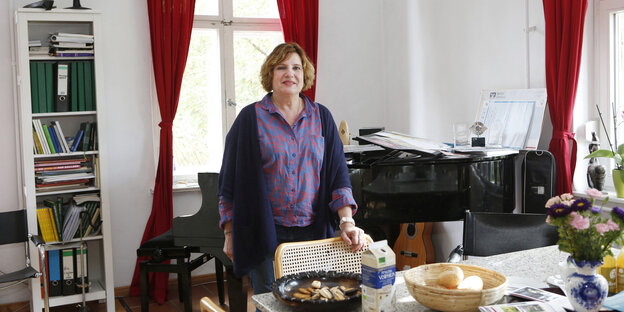 Eine Frau steht in ihrem Wohnzimmer und guckt in die Kamera Eine Frau steht in ihrem Wohnzimmer und guckt in die Kamera