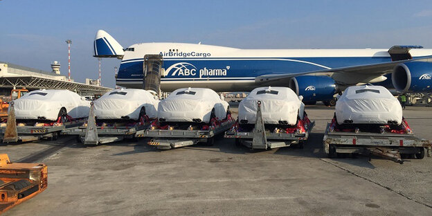 Verhüllte Fahrzeuge vor einem Flugzeug Verhüllte Fahrzeuge vor einem Flugzeug
