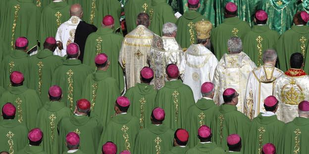 Viele Männer mit Roten Mützen und grünen Umhängen. Ein paar dazwischen haben weiße Kutten an. Es sind Bischöfe auf einer Messe im Vatikan Viele Männer mit Roten Mützen und grünen Umhängen. Ein paar dazwischen haben weiße Kutten an. Es sind Bischöfe auf einer Messe im Vatikan