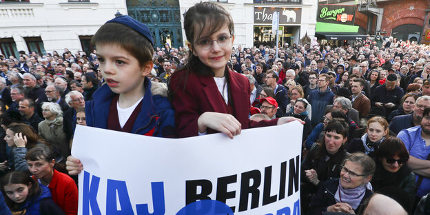 Zwei Kinder auf einer Demo, eines trägt eine Kippa