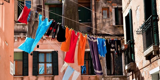 Bunte Wäsch trocknet vor einem orangefarbenen Haus in der Sonne