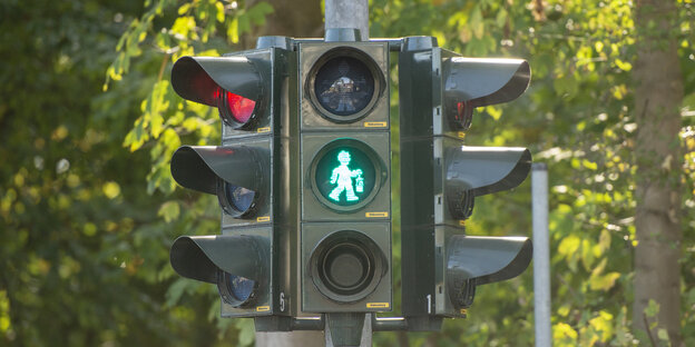 Eine Ampel zeigt in gehendes grünes Ampelmännchen das ein Gefäß in der Hand hält