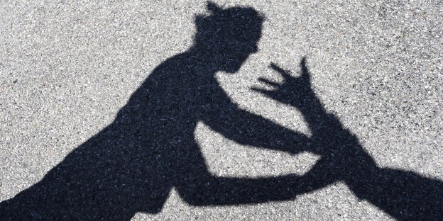 Schattenbild einer Frauenfigur, de von einer Hand ergriffen wird Schattenbild einer Frauenfigur, de von einer Hand ergriffen wird
