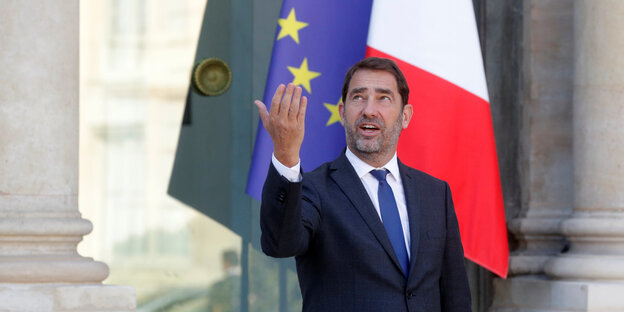 Christophe Castaner, der neue französische Innenminister, steht vor einer französischen und einer europäischen Flagge, blickt nach oben und hebt den angewinkelten rechten Arm wie zum Gruß Christophe Castaner, der neue französische Innenminister, steht vor einer französischen und einer europäischen Flagge, blickt nach oben und hebt den angewinkelten rechten Arm wie zum Gruß