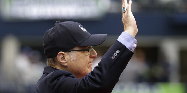 Paul Allen mit schwarzer Base-Cap im Profil hebt die rechte Hand und winkt Paul Allen mit schwarzer Base-Cap im Profil hebt die rechte Hand und winkt