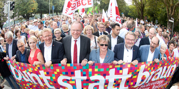 Viele Menschen tragen ein breites Banner auf einer Demo vor sich her Viele Menschen tragen ein breites Banner auf einer Demo vor sich her
