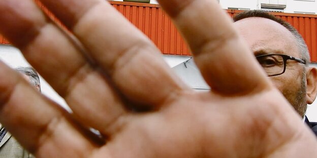 Eine Hand greift in Richtung Kameralinse, respektive Betrachter*in Eine Hand greift in Richtung Kameralinse, respektive Betrachter*in
