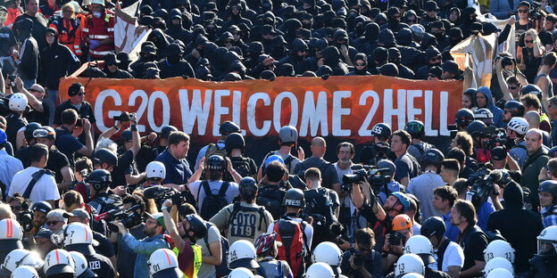 Eine Menschenmenge trägt ein Banner mit der Aufschrift "G20 Welcome to Hell" Eine Menschenmenge trägt ein Banner mit der Aufschrift "G20 Welcome to Hell"
