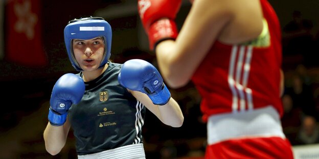 Eine Frau mit blauen Boxhandschuhen links kämpft gegen eine Frau mit roten Boxhandschuhen rechts. Eine Frau mit blauen Boxhandschuhen links kämpft gegen eine Frau mit roten Boxhandschuhen rechts.