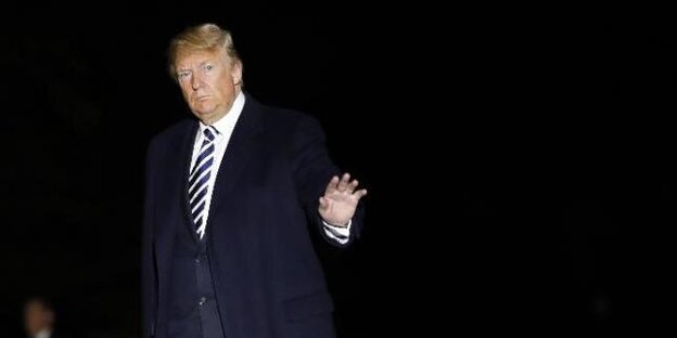 Donald Trump steht mit einem blauen Anzug bekleidet vor schwarzem Hintergrund. Donald Trump steht mit einem blauen Anzug bekleidet vor schwarzem Hintergrund.