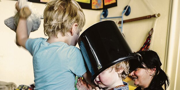 Zwei Kinder beim Spielen. Eines davon hat einen Eimer auf dem Kopf. Zwei Kinder beim Spielen. Eines davon hat einen Eimer auf dem Kopf.