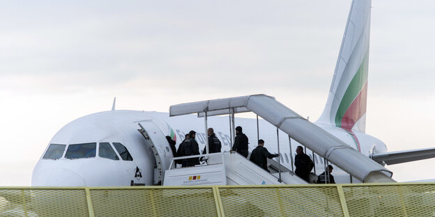 Auf der Treppe eines Flugzeugs stehen Polizisten