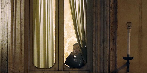 Matteo Salvini steht, halb von einem Vorhang verdeckt, an einem hell erleuchteten Fenster und guckt nach draußen Matteo Salvini steht, halb von einem Vorhang verdeckt, an einem hell erleuchteten Fenster und guckt nach draußen