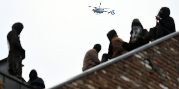 Braunkohlegegner auf einem Dach, darüber ein Hubschrauber Braunkohlegegner auf einem Dach, darüber ein Hubschrauber